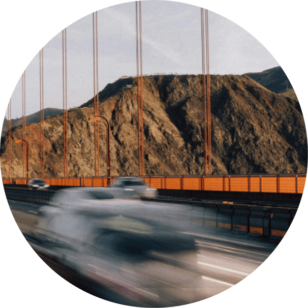 Cars blurred in motion crossing the Golden Gate Bridge, with hills behind
